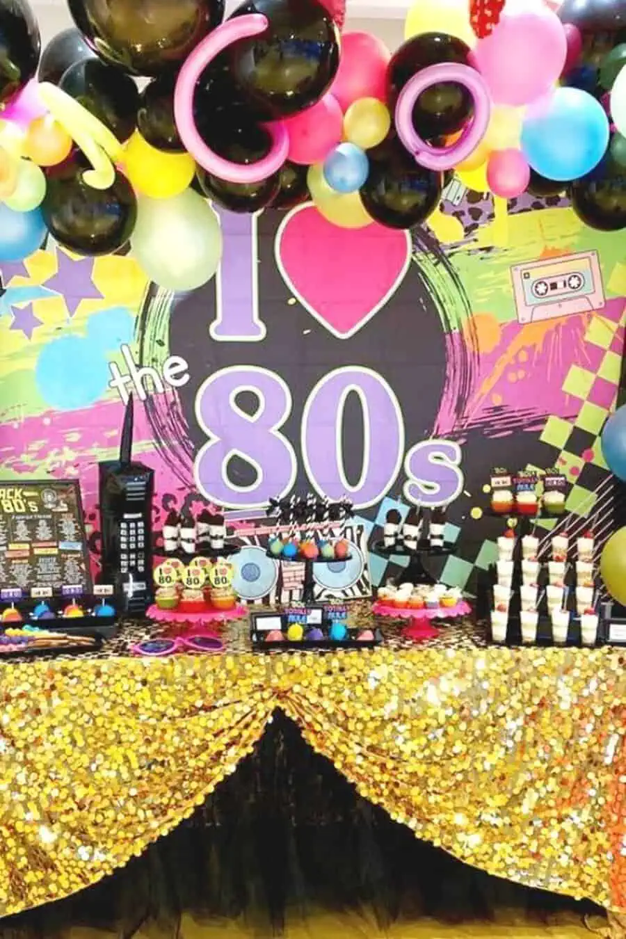 80s-themed 40th birthday party table with retro decor, colorful balloons, and gold sequin cloth.