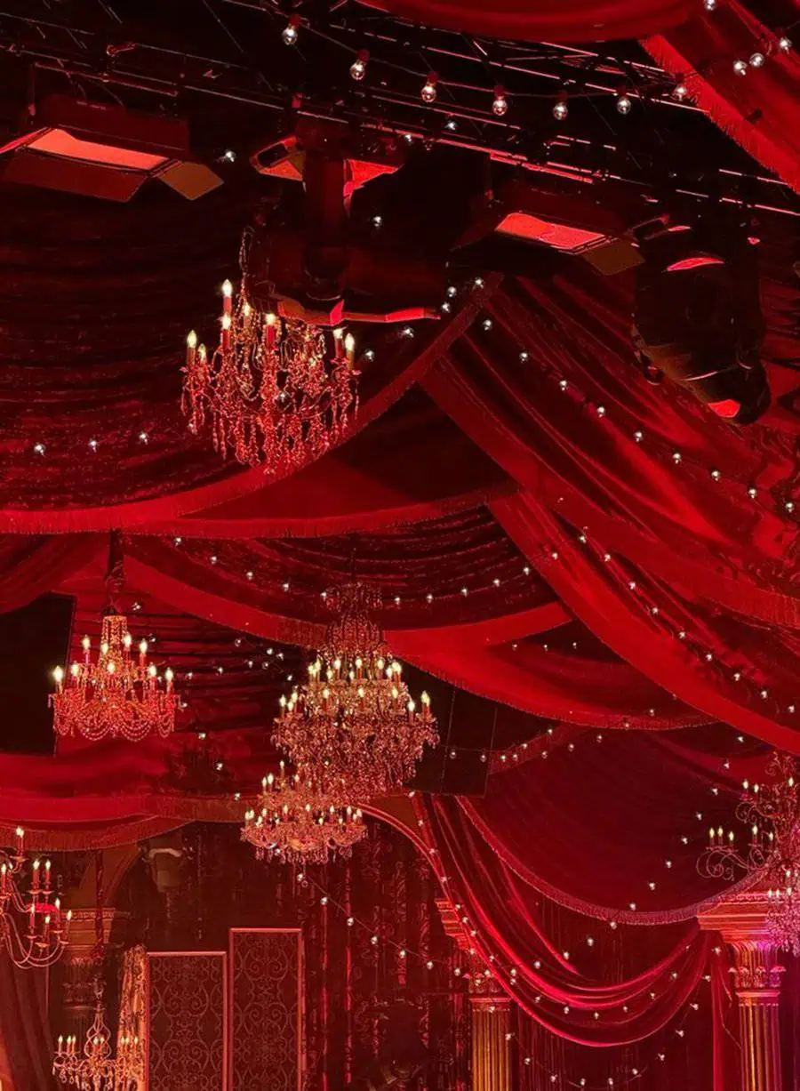 Luxurious 40th birthday celebration with red drapes, crystal chandeliers, and elegant lighting.