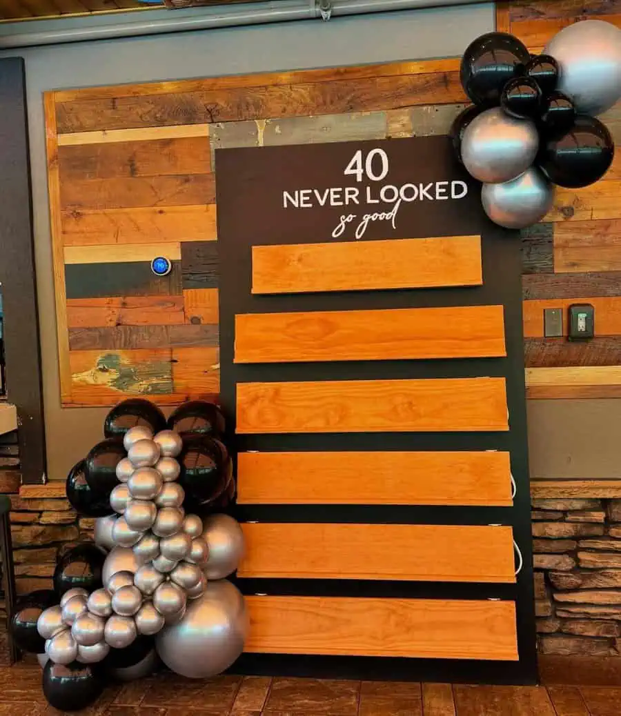 "40 Never Looked So Good" wooden display with black and silver balloons for 40th birthday celebration ideas.