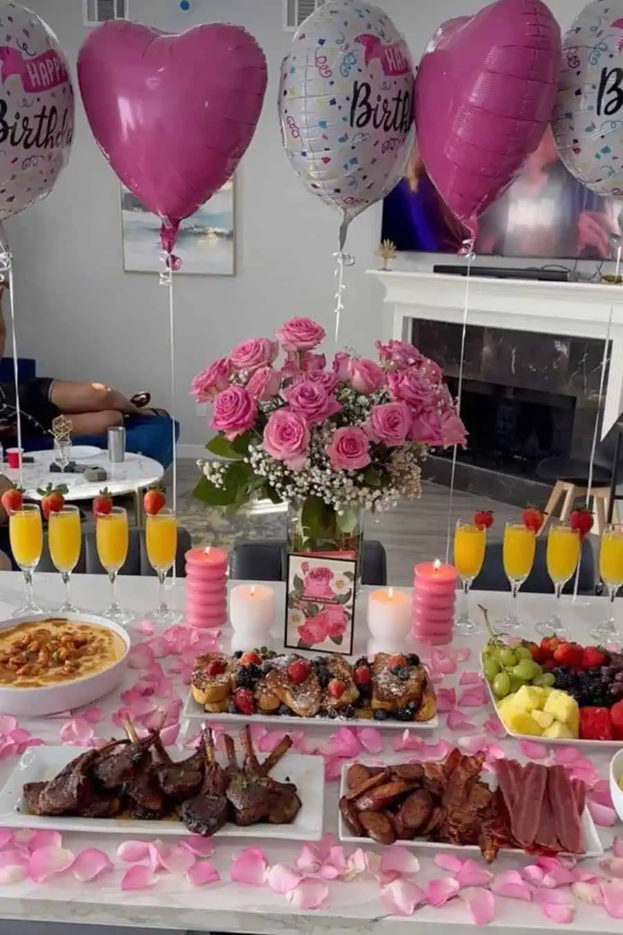 Pink-themed 40th birthday celebration with heart-shaped balloons, pink roses, candles, and a luxurious brunch spread.