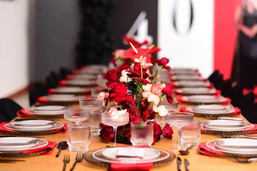 Elegant 40th birthday table setting with red floral centerpiece and black and red accents.