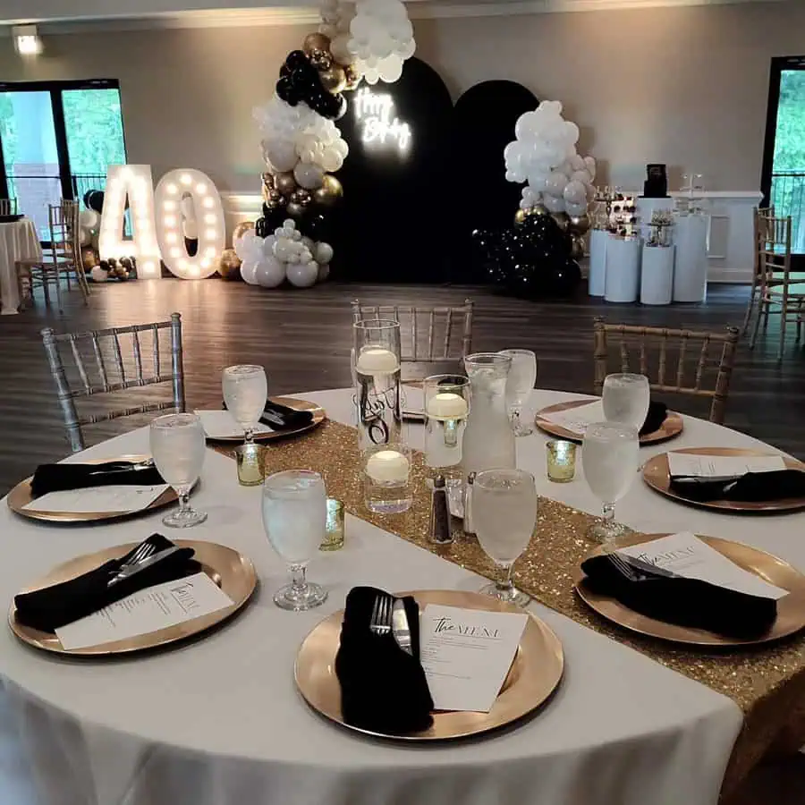 Opulent 40th birthday table design with black and gold theme, candles, and floral accents.