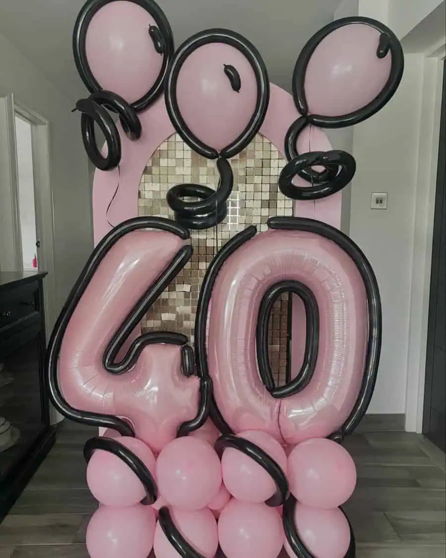 Pink and black balloon display with "40" centerpiece for 40th birthday celebration ideas.