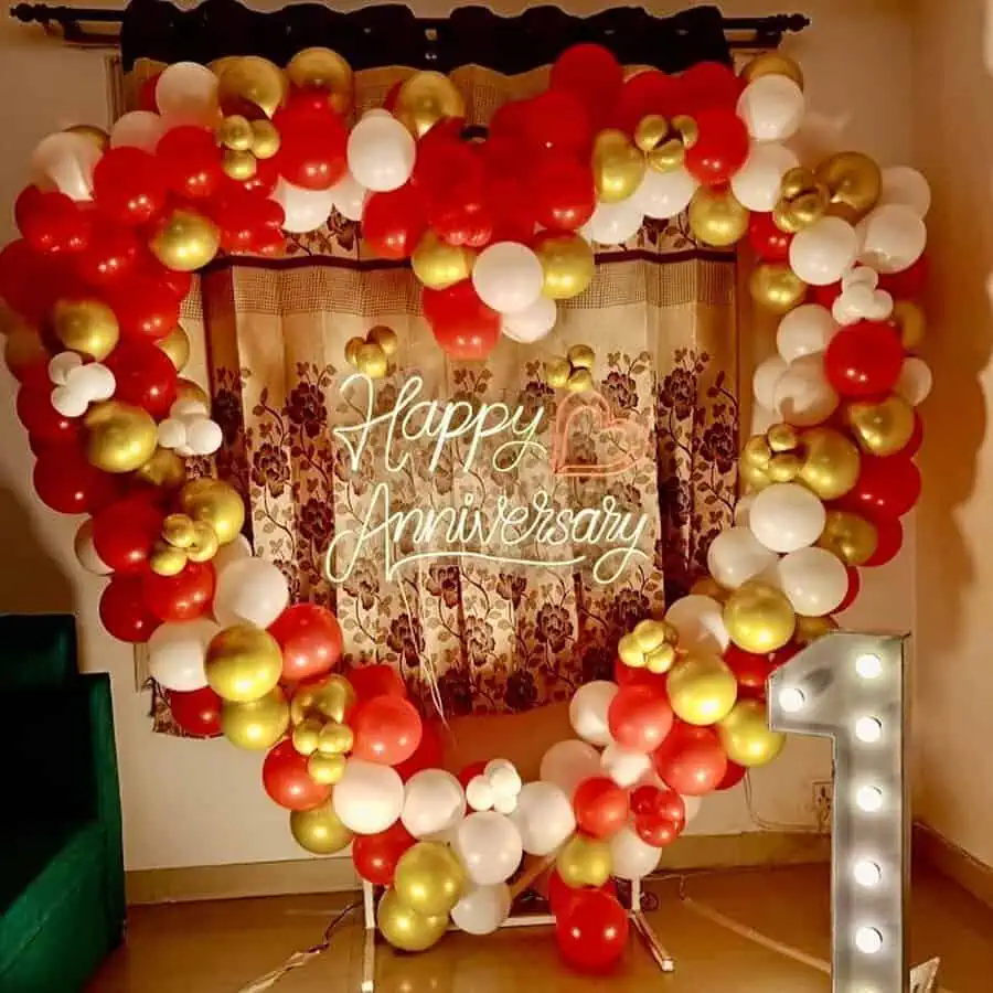 Heart-shaped balloon arrangement with "Happy Anniversary" neon sign and a lit number one.