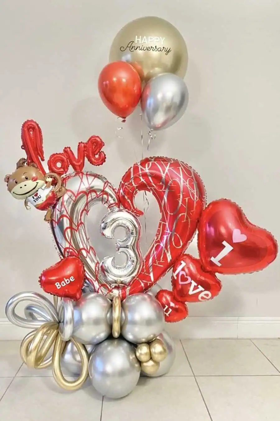 Anniversary balloon arrangement with red, silver, and gold balloons featuring "Love" and "3 years."