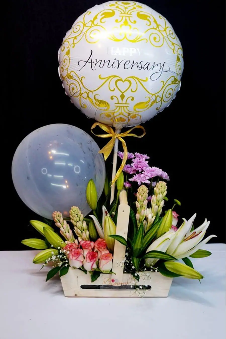 Elegant anniversary floral arrangement with lilies, roses, and a "Happy Anniversary" balloon.