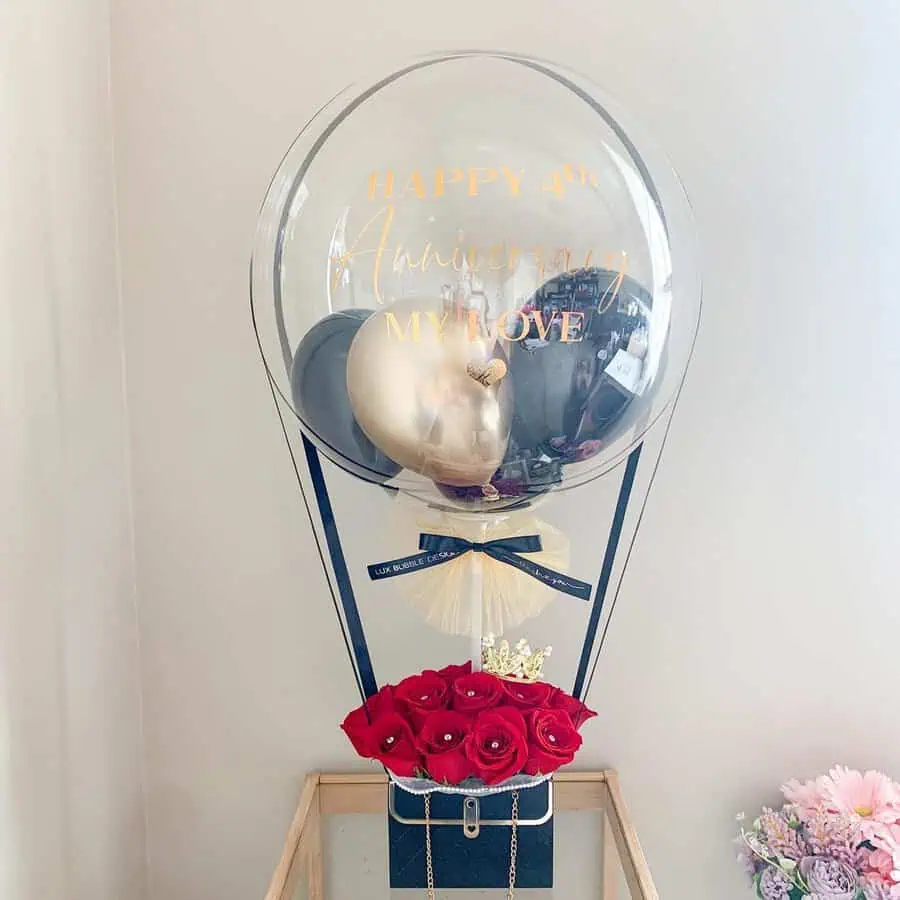 A luxurious anniversary gift box with roses and a personalized balloon message.