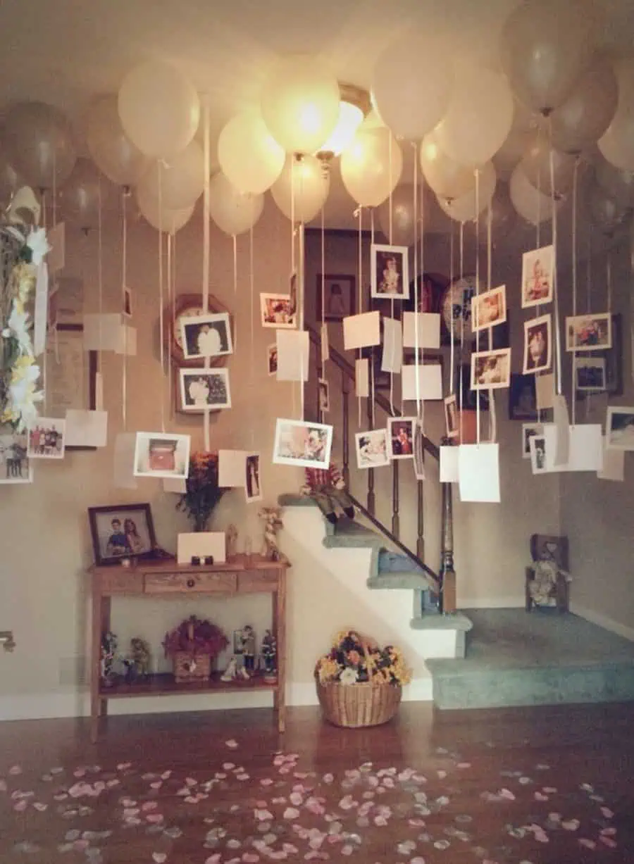 A romantic display of memories with hanging photos and balloons for a sentimental anniversary celebration.