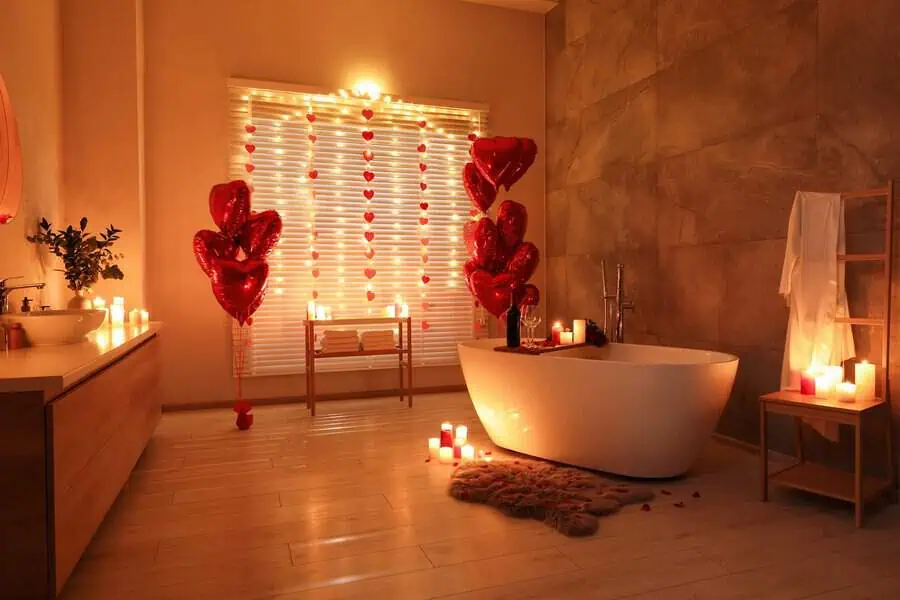 A cozy, candlelit bath setup with heart-shaped balloons for a romantic anniversary evening.