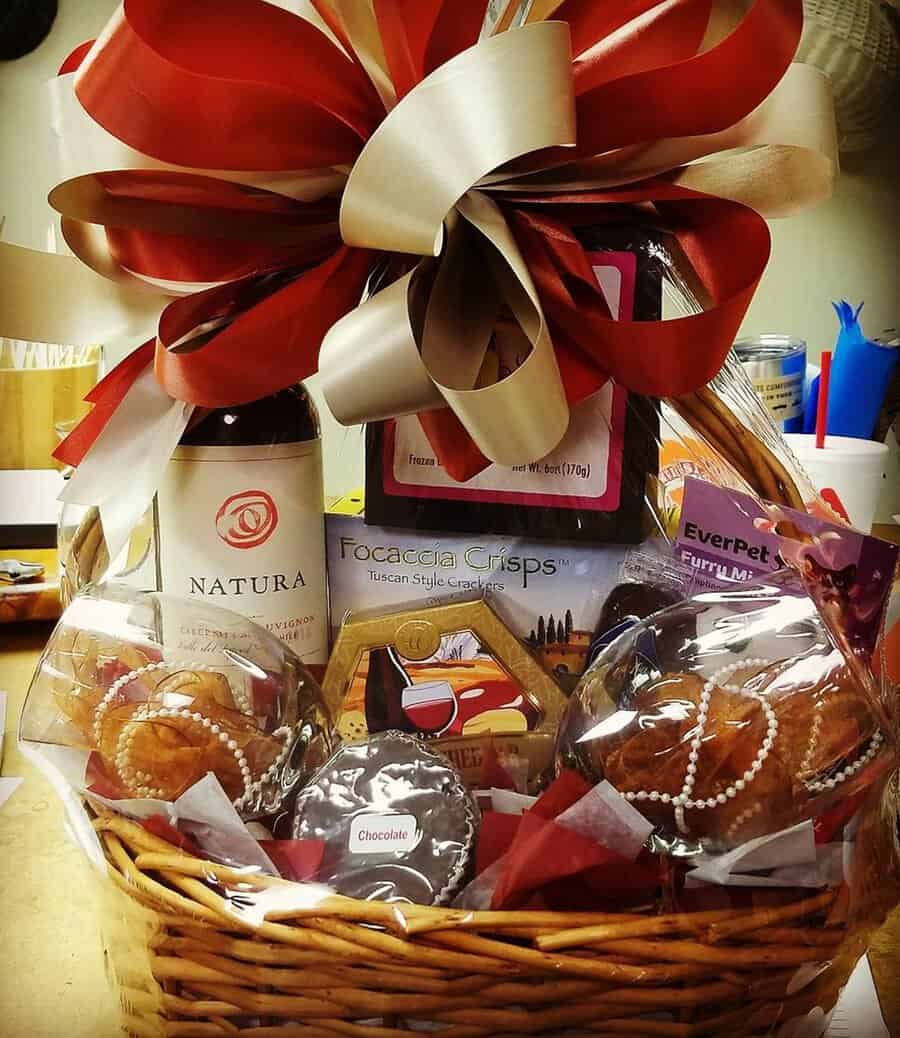 Anniversary gift basket with wine, crackers, chocolates, and a decorative red bow.