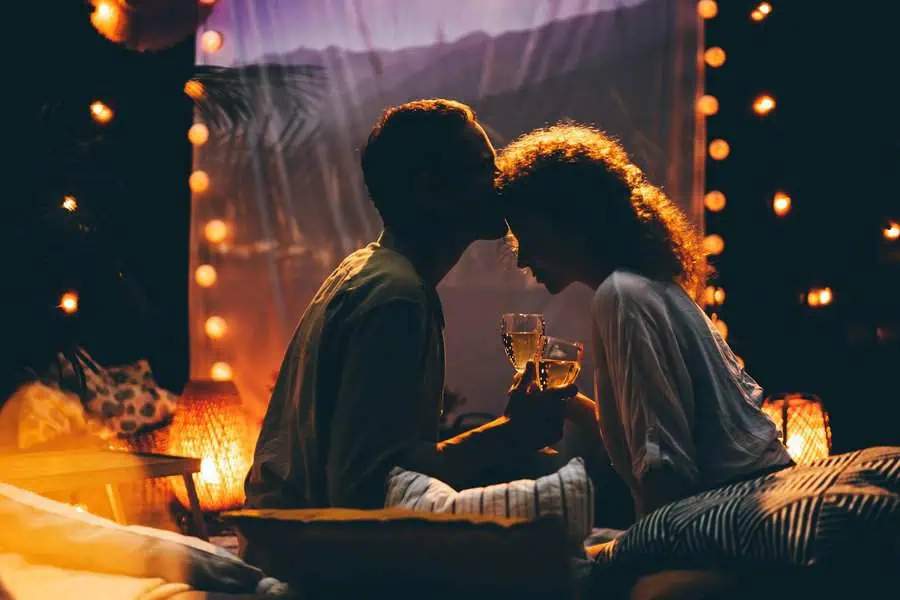 Romantic anniversary celebration with a couple sharing a toast under cozy string lights.