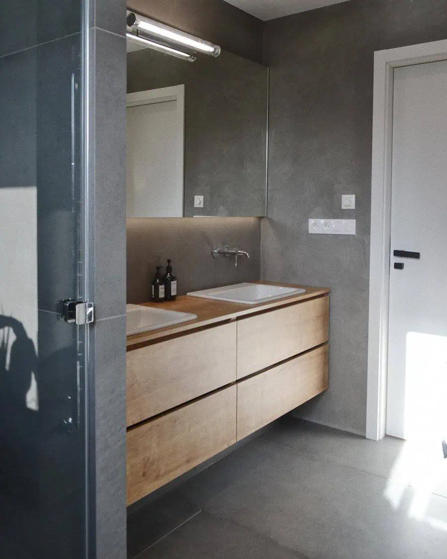 Modern bathroom with wooden floating vanity, grey floor tiles, and large mirror.