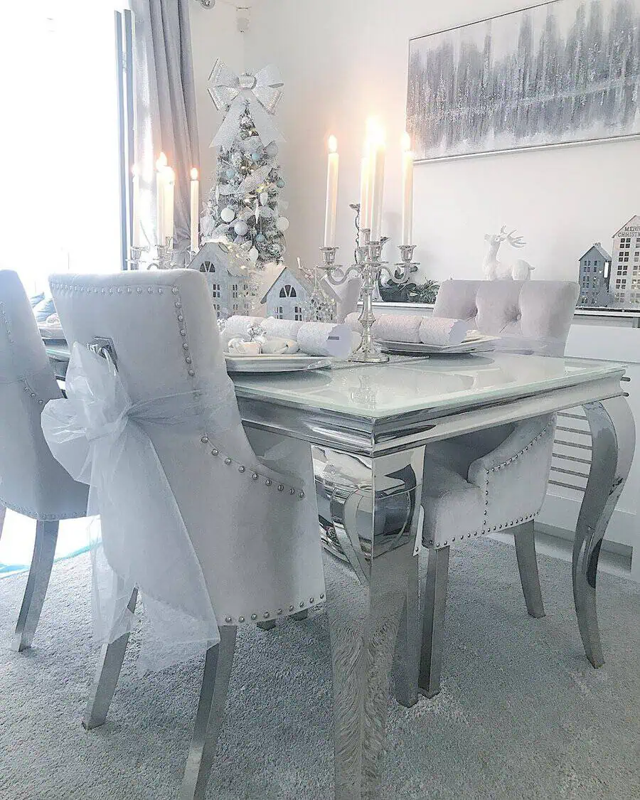 Elegant Christmas dining table with silver decor, candles, and a white festive theme.