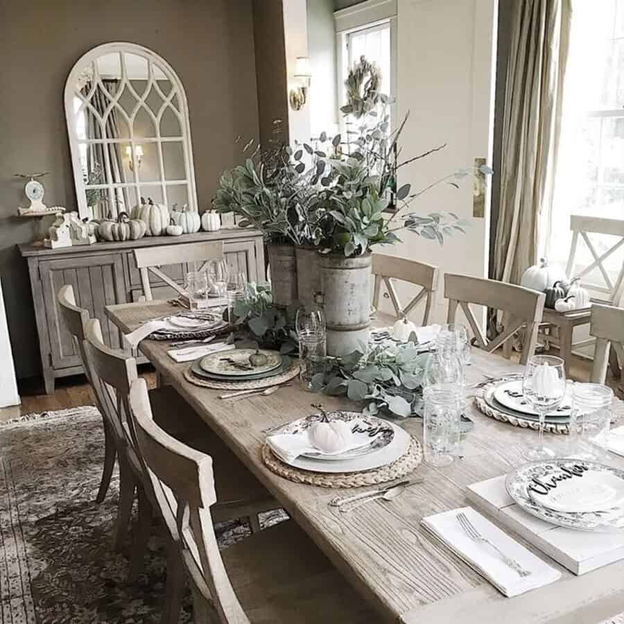 Festive Christmas dining table with eucalyptus greenery, pumpkins, and elegant rustic decor.