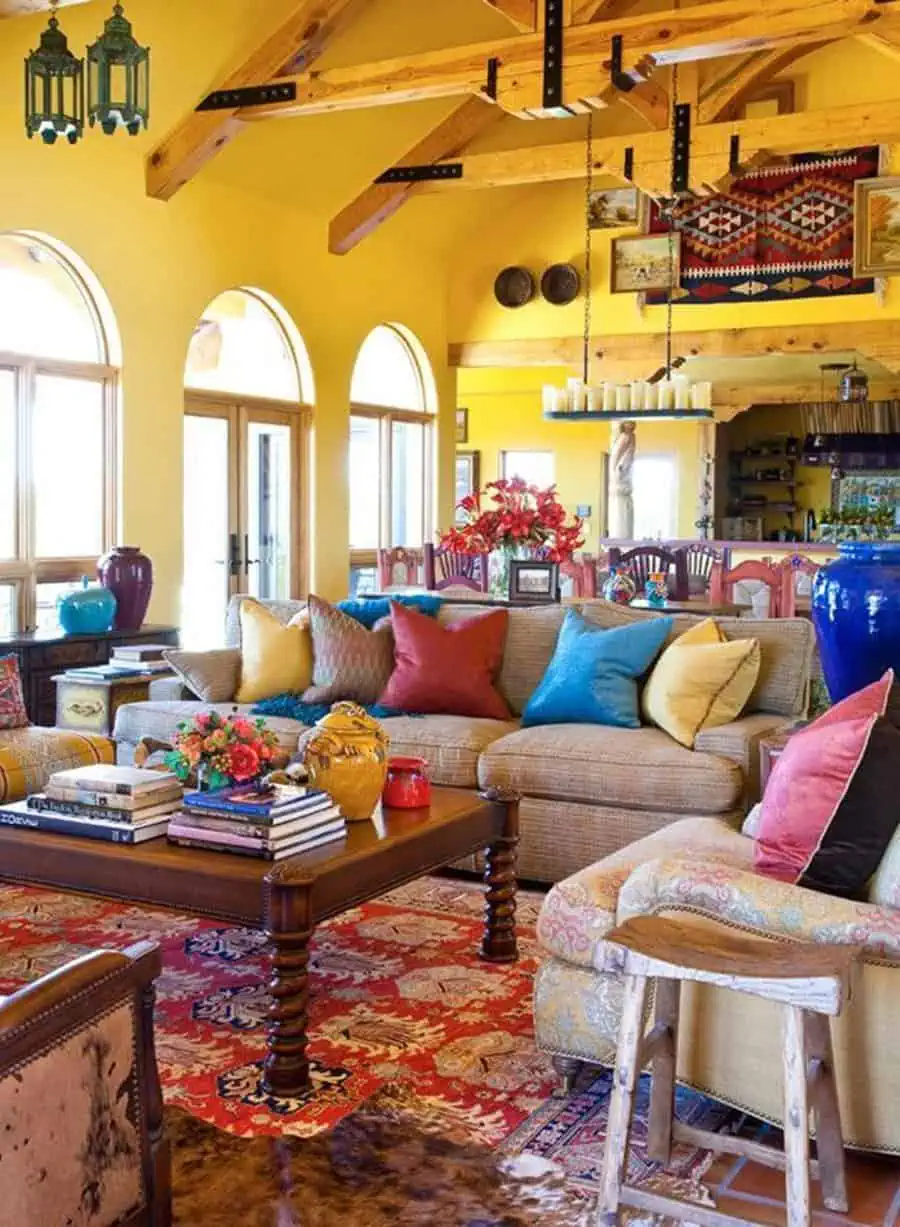 Colorful Spanish-style living room with yellow walls, wooden beams, arched windows, and vibrant decor.