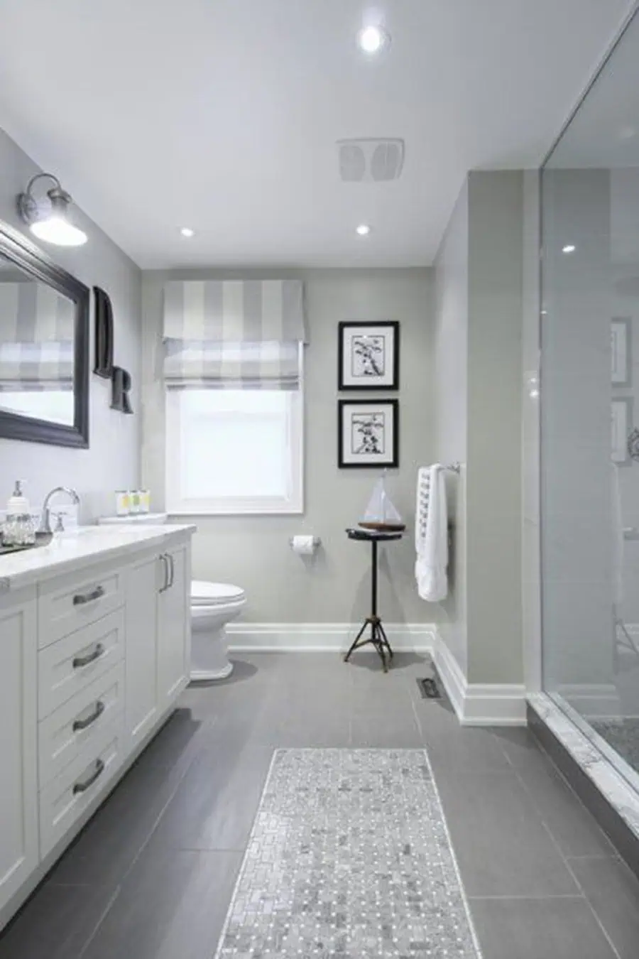 Bathroom featuring grey floor tiles with a contrasting border of small mosaic tiles, complementing the light grey walls and white fixtures.