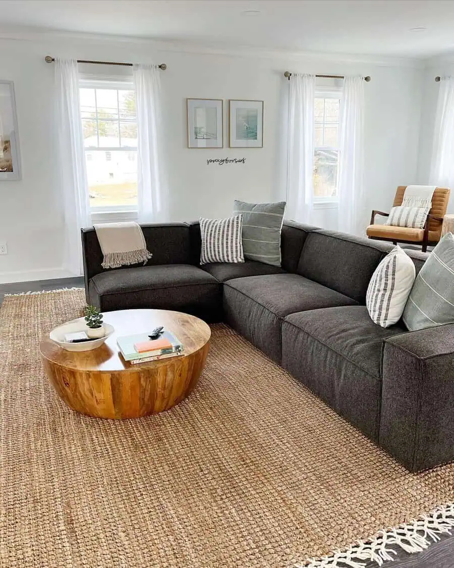 Dark grey sectional sofa with striped cushions, wooden coffee table, and bright airy decor.