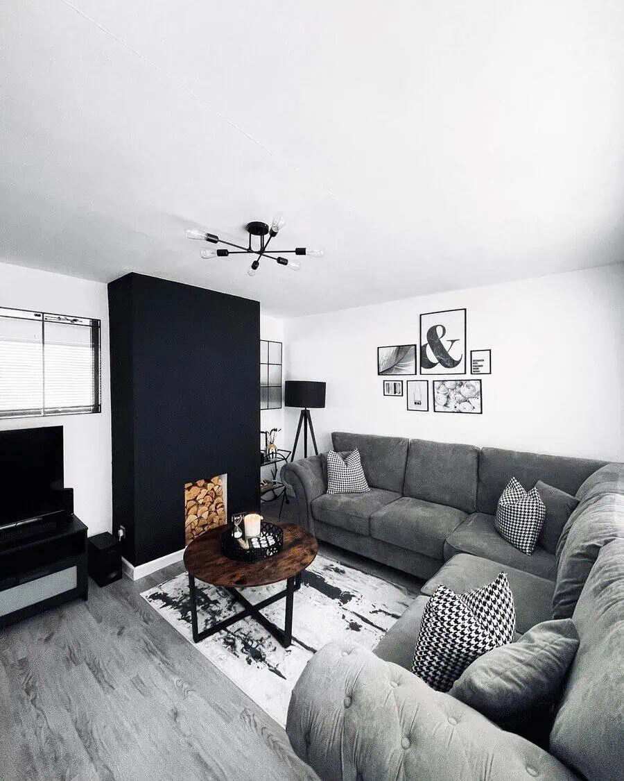 Dark grey sectional sofa with houndstooth cushions, black accent wall, and modern monochrome decor.