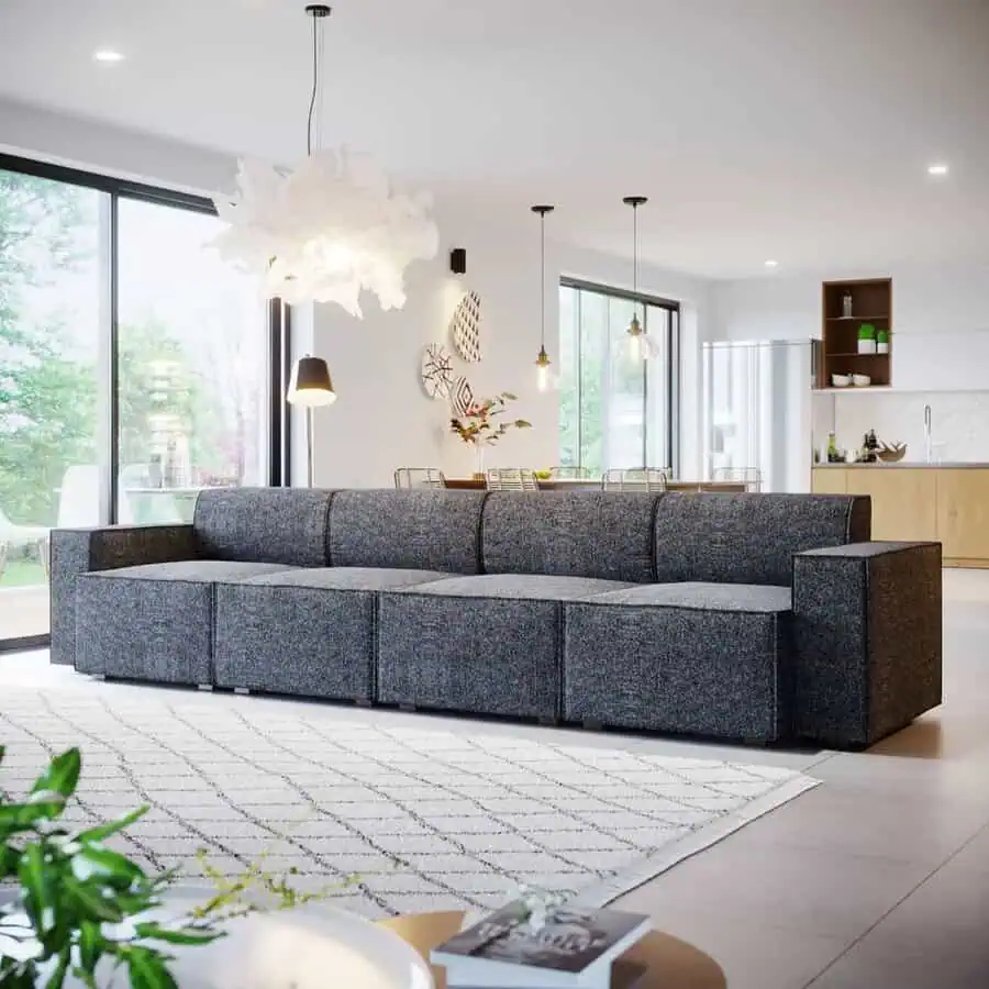 Spacious dark grey modular sofa in a bright open-plan living area, paired with modern pendant lighting and natural accents.