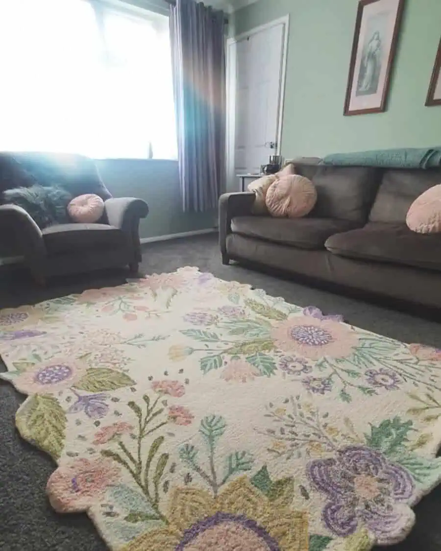 Cozy living room with dark grey sofas, pastel pink cushions, and a floral rug.