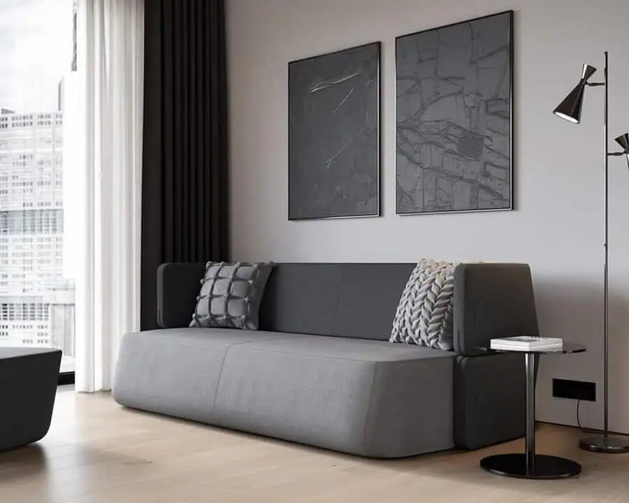 Modern dark grey sofa with textured cushions, minimalist decor, and abstract wall art.