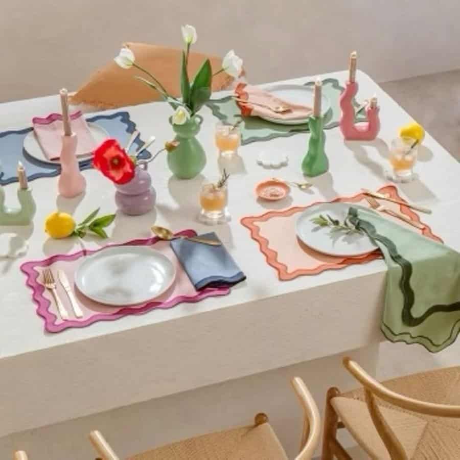 Casual dining table with colorful placemats, quirky vases, fresh flowers, and playful decor.