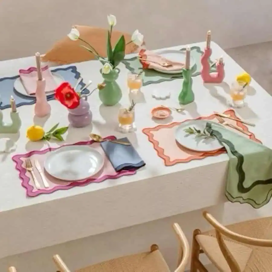 Casual dining table with colorful placemats, quirky vases, fresh flowers, and playful decor.