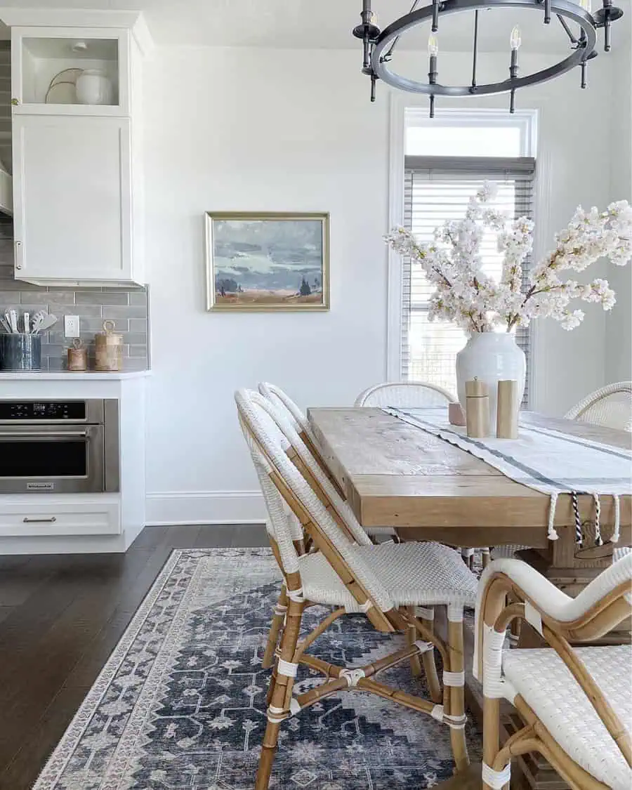 Dining table with a simple vase arrangement, wicker chairs, and rustic decor accents.