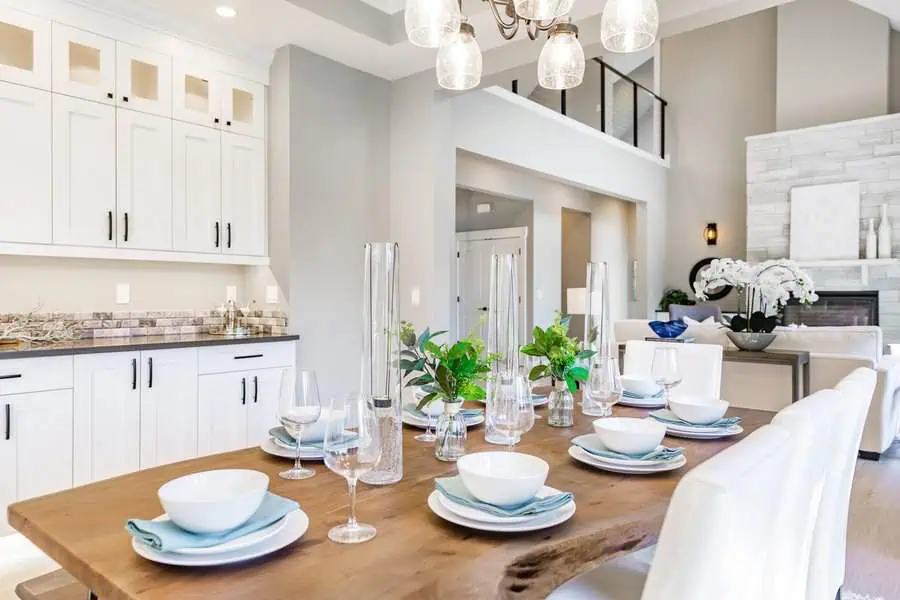 Elegant dining table with a live-edge wooden top, white tableware, and green floral accents.