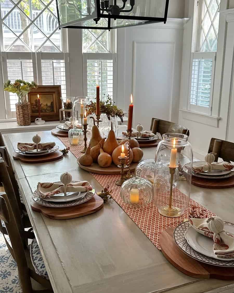 Elegant fall dining table with pumpkins, candles, and seasonal table settings.