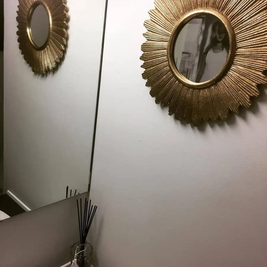 Gold sunburst feng shui mirror reflecting a minimalist wall and decor accents.