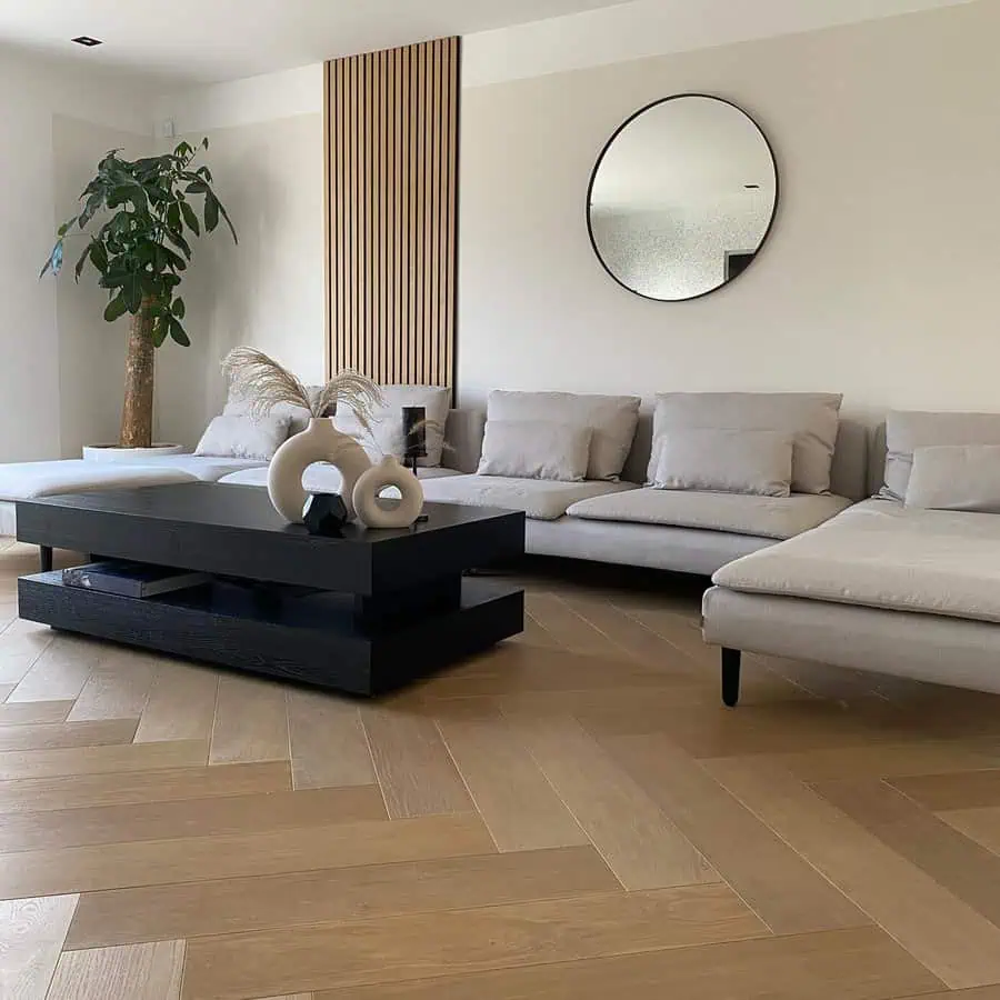 Minimalist living room with round feng shui mirror, neutral sofa, and modern black coffee table.