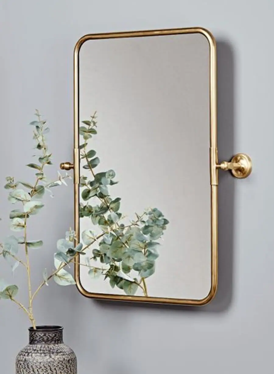 Wall-mounted rectangular feng shui mirror with gold frame and eucalyptus vase decor.