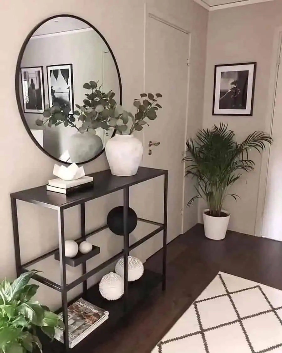 Entryway with round feng shui mirror, black console table, plants, and modern decor accents.