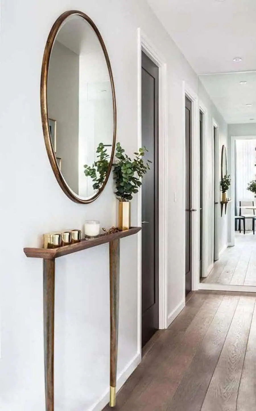 Hallway with oval feng shui mirror, slim console table, and gold decor accents.