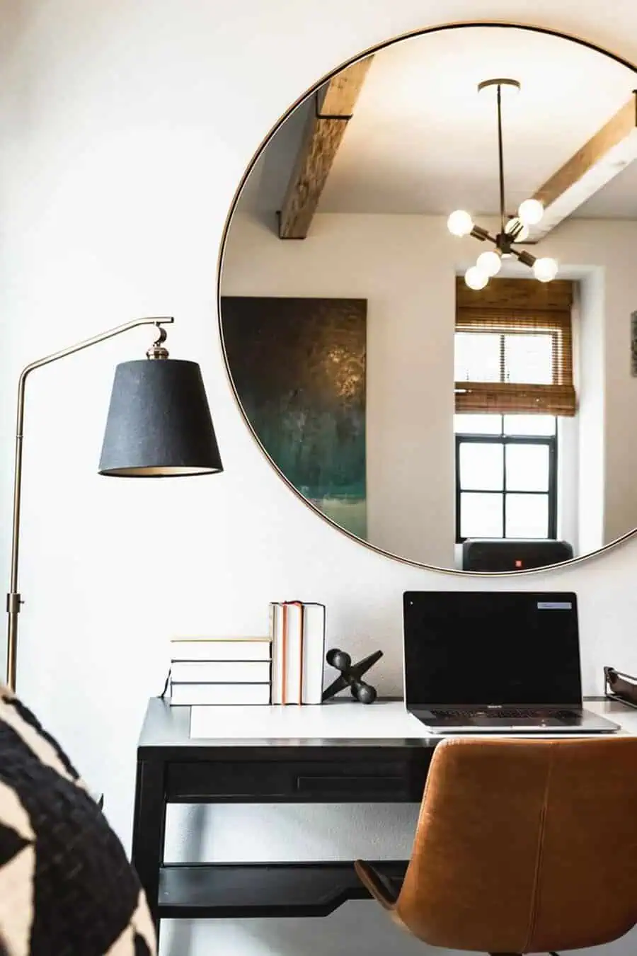 Home office with round feng shui mirror, desk lamp, laptop, and modern decor elements.