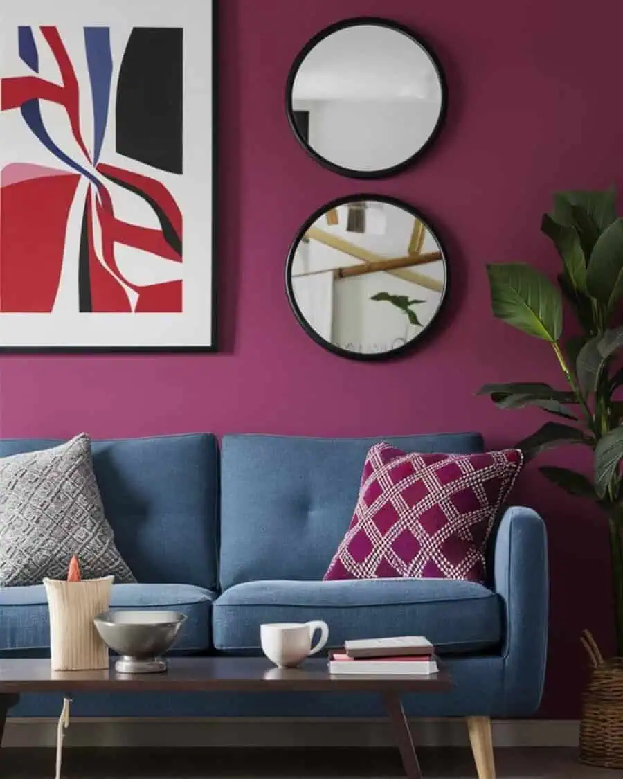 Purple wall with round feng shui mirrors, abstract art, and blue sofa with vibrant accents.