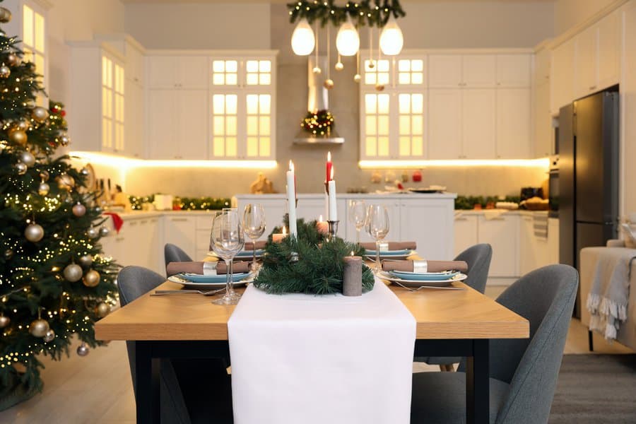 Christmas dining table with festive greenery, candles, and elegant table settings.
