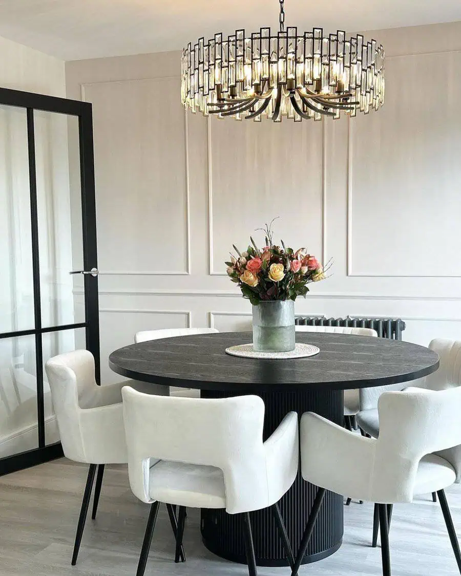 Elegant dining area with a black round table, white chairs, and a floral centerpiece.