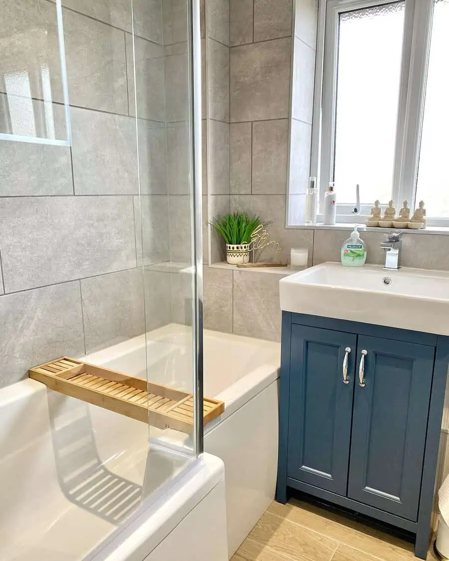 Bathroom with grey floor tiles featuring dark grout, tiled walls, and wooden accents.