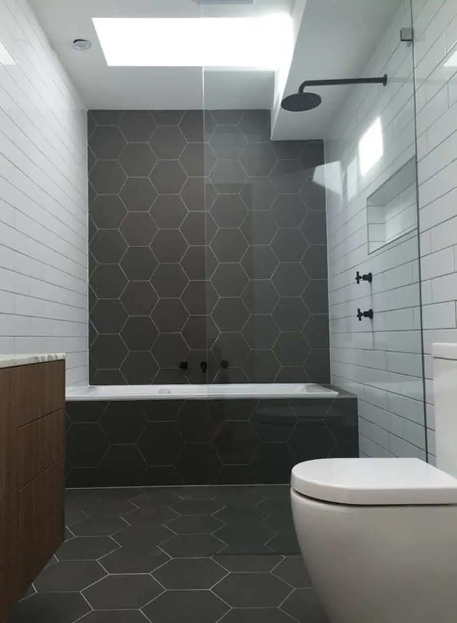 Modern bathroom with grey hexagonal floor tiles, white subway walls, and glass shower enclosure.