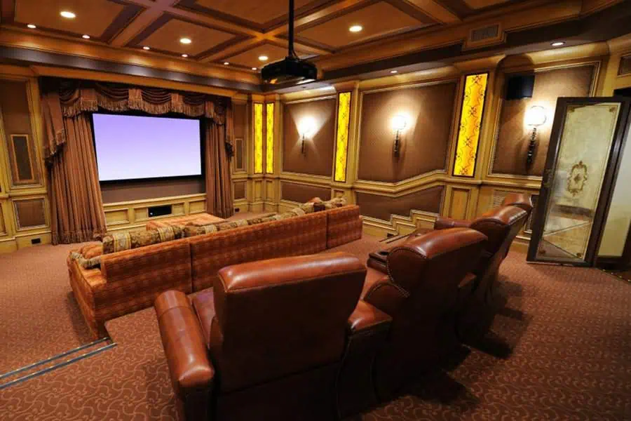 Classic home theater with ornate decor, rich leather seats, and warm ambient lighting.