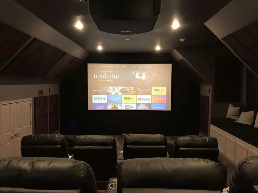 Modern attic home theater with reclining leather chairs, dim lighting, and cozy seating nooks.