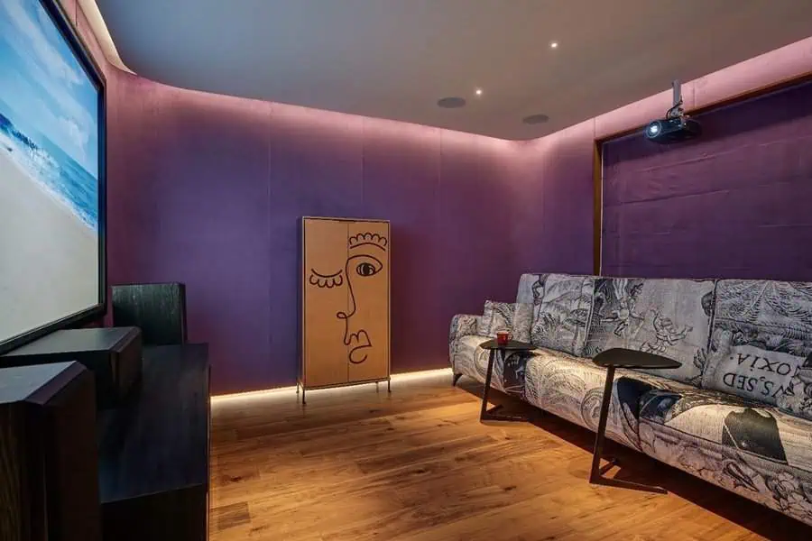 Contemporary home theater with vibrant purple walls, artistic furniture, and cozy ambiance lighting.