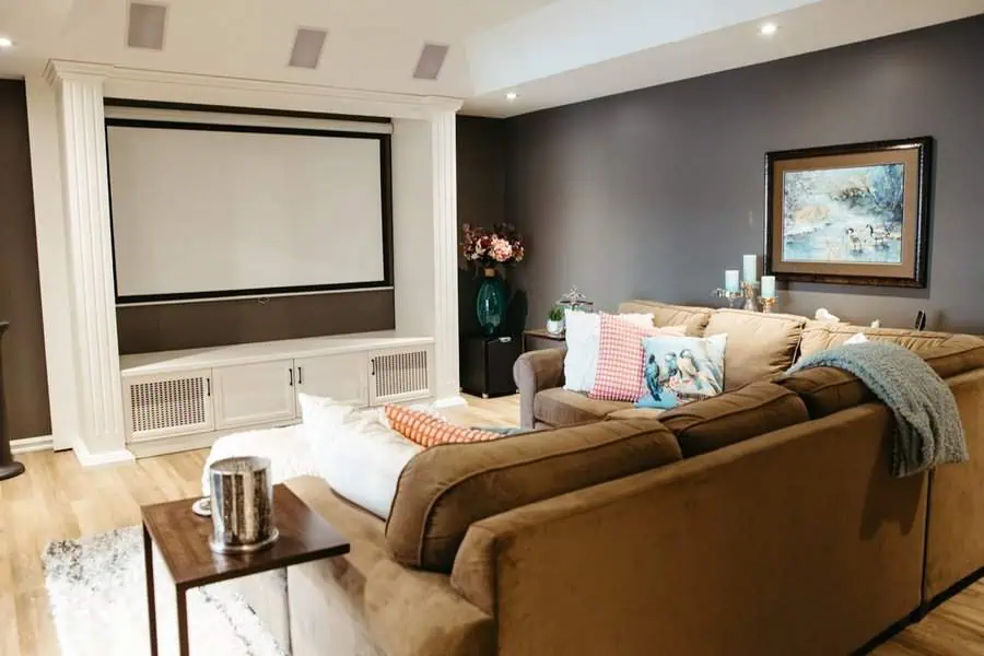 Cozy home theater with sectional seating, warm tones, and a stylish projector screen.