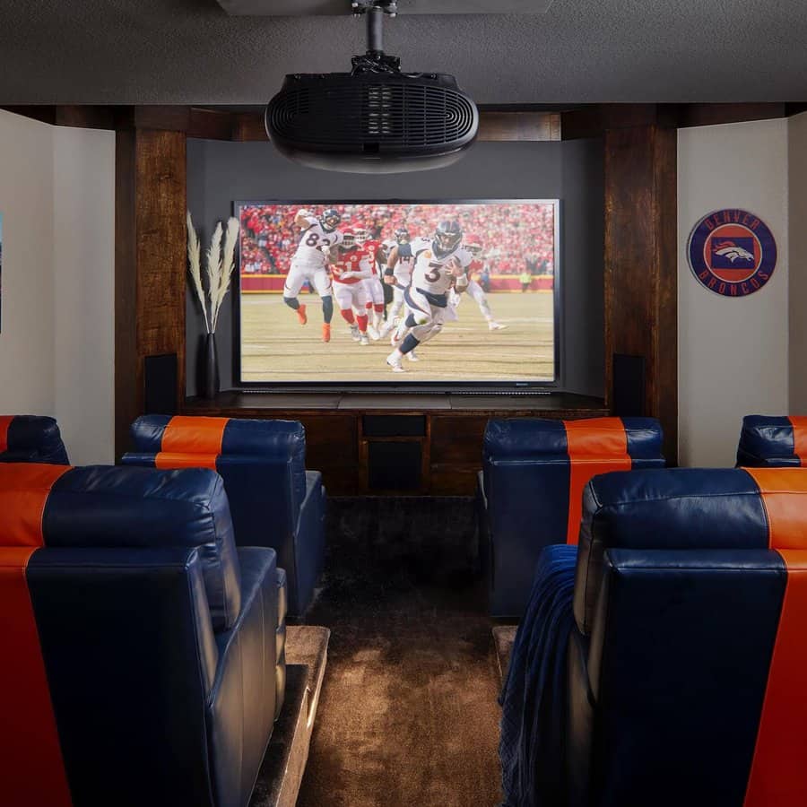 Sports-themed home theater with team-inspired seating, wooden accents, and a large screen for game days.
