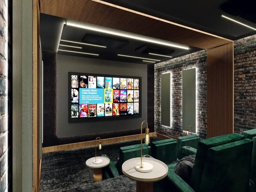 Modern home theater with exposed brick walls, velvet green seating, and a sleek movie display.