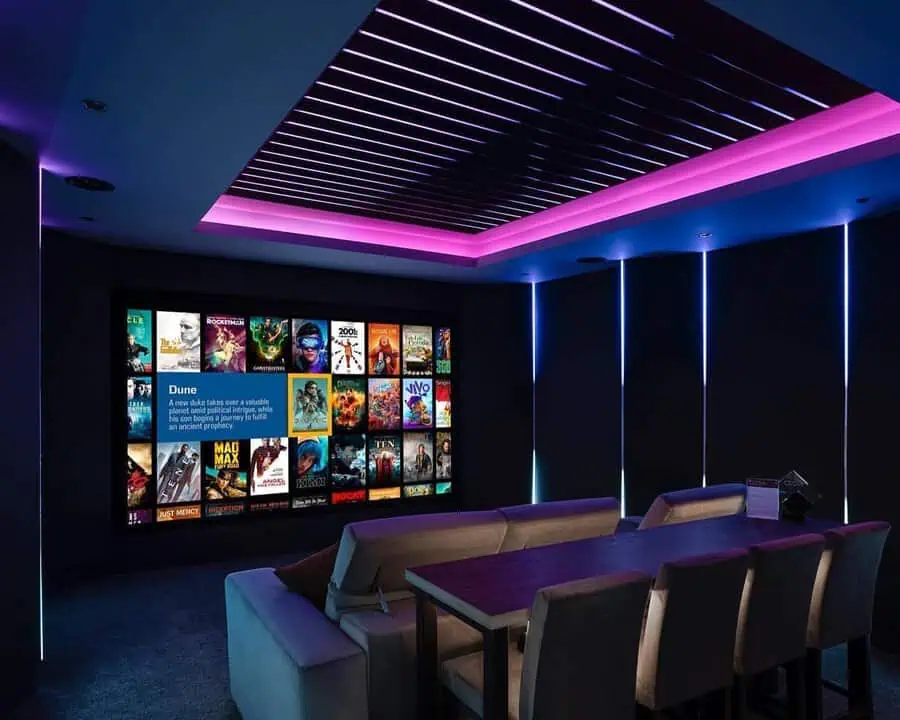 Modern home theater featuring a vibrant LED ceiling, comfortable seating, and a large screen displaying movie covers.