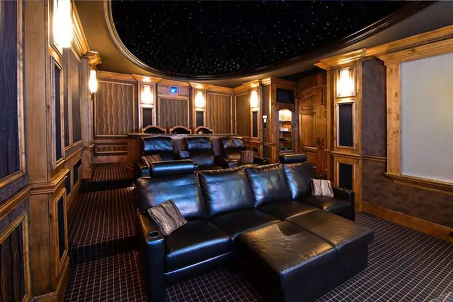 Luxurious home theater with a wooden interior, leather seating, and a starlit ceiling for an immersive movie experience.