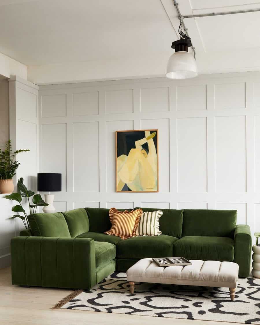 Living room corner with a green sectional sofa, abstract art, plants, and a patterned rug.